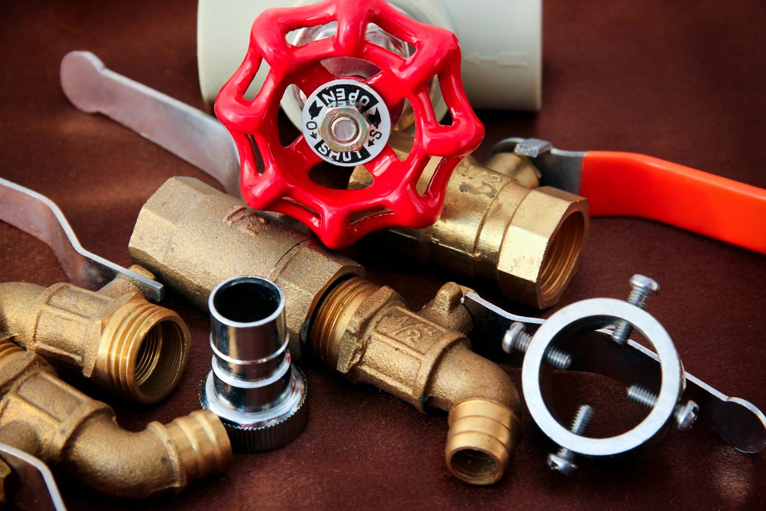 Brass plumbing fittings and a red shutoff valve
